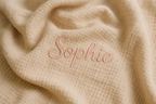 je veut une couverture de bébé en gaz de coton beige avec brodé dessus le prénom Sophie couleur rose